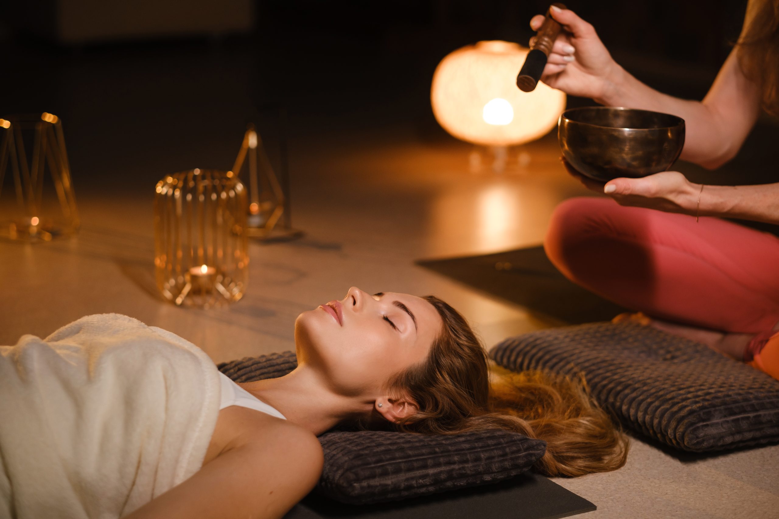 a girl lying on the floor relaxes to the sounds of a tibetan bowl in the gym