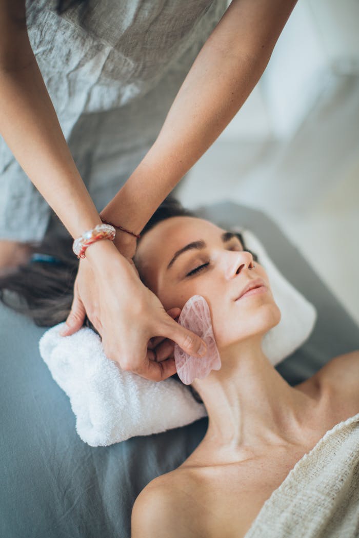 a person holding a gua sha while putting on a woman s face 3865562.jpeg